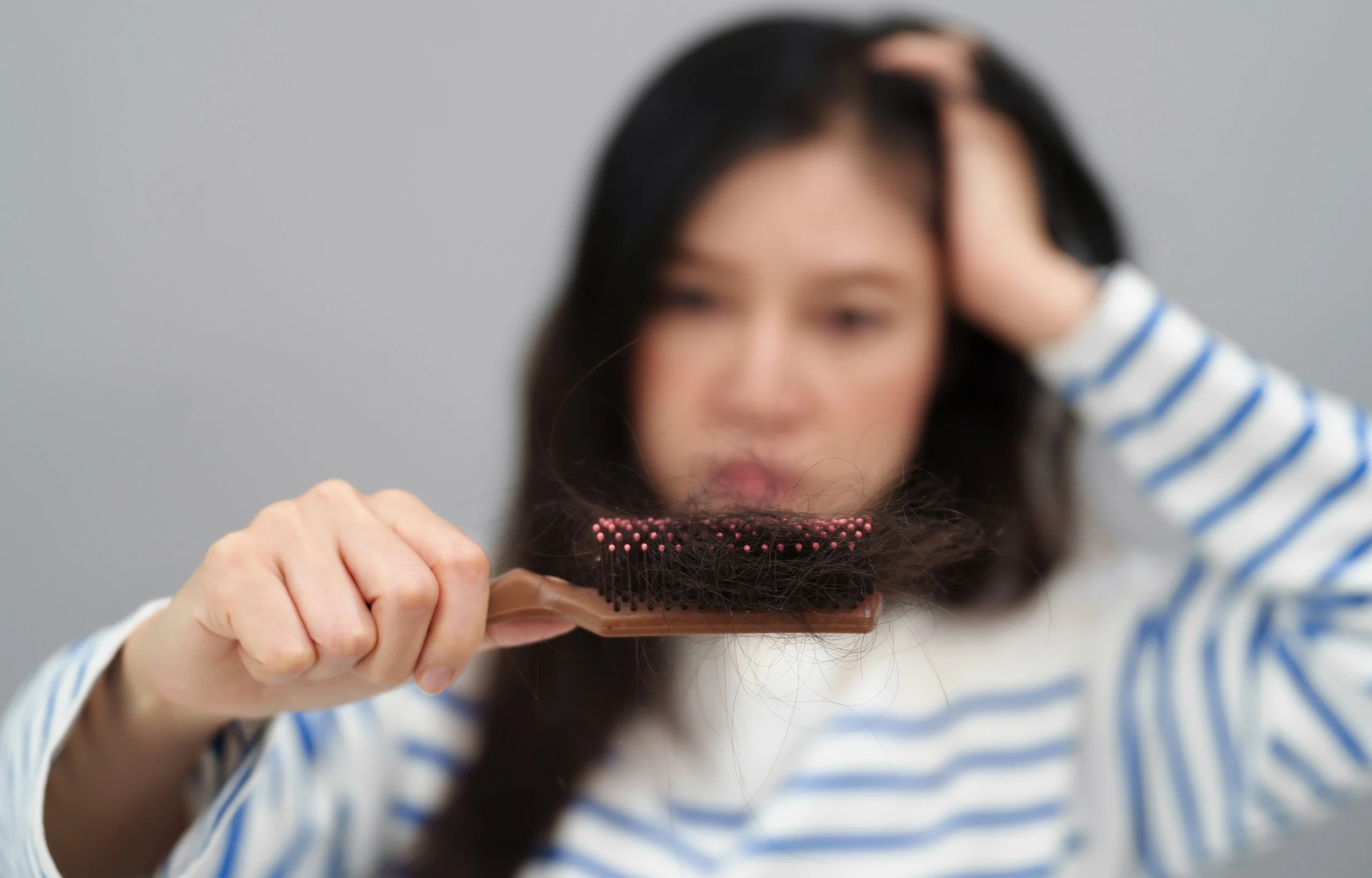 Donna che osserva i capelli sottili nella spazzola