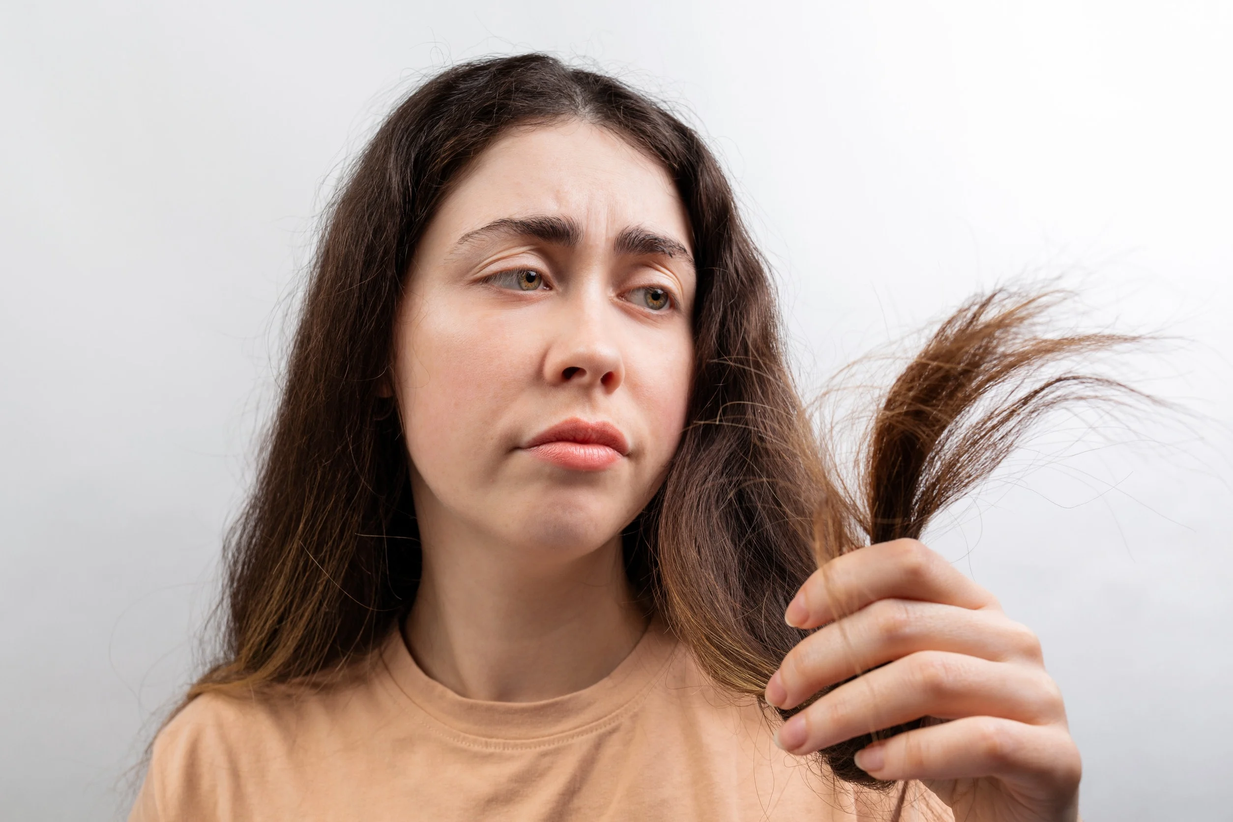 Una donna preoccupata per l'assottigliamento dei capelli, che spesso precede o accompagna la caduta.