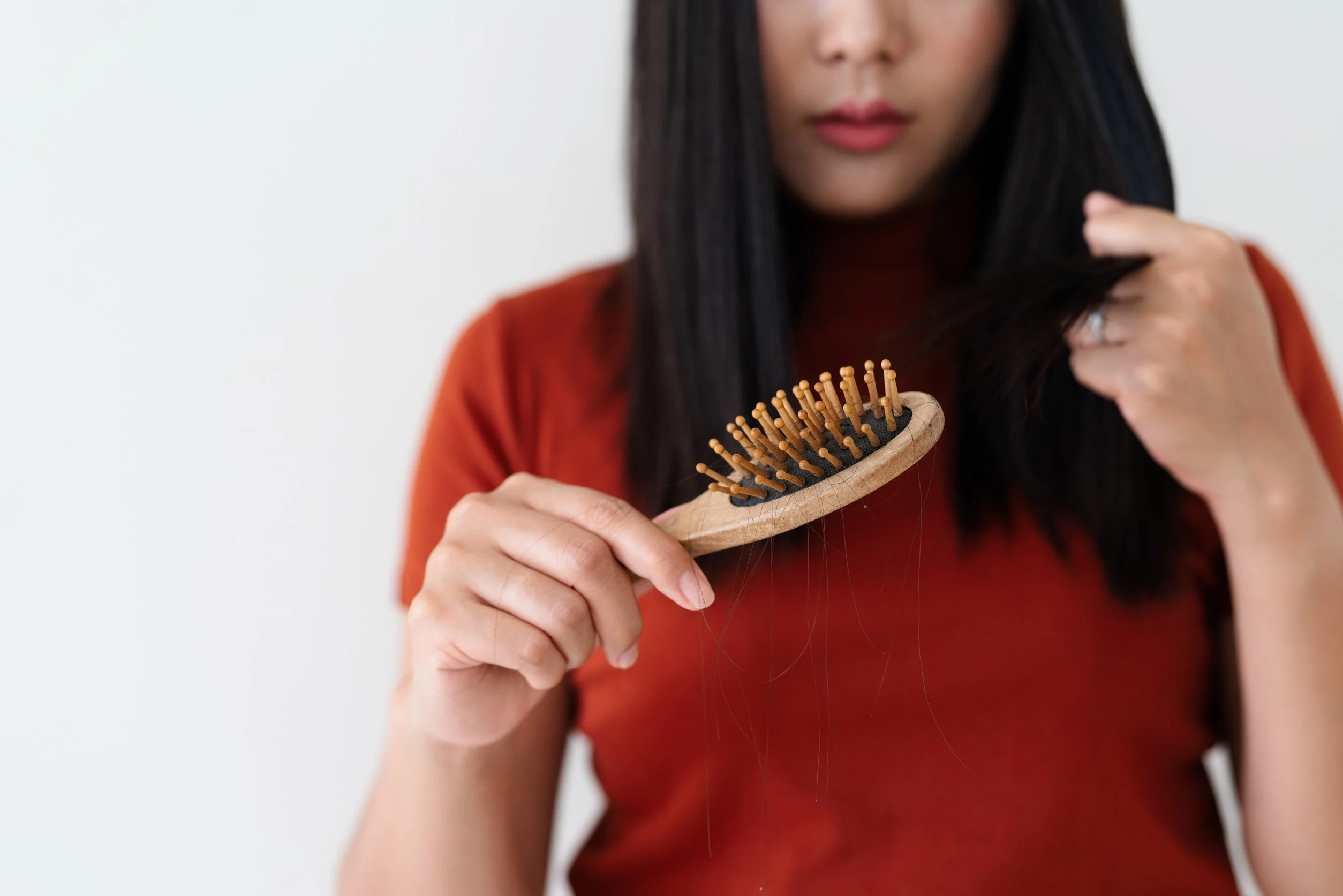 Una donna con dei capelli nella spazzola preoccupata per la caduta.